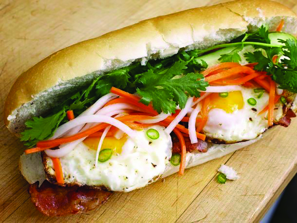 A long egg baguette filled with bacon, cilantro, and carrot