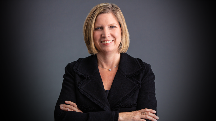 Jennifer Rumsey, Cummins CEO sports a blonde bob and a black jacket in this photo studio image with a grey background